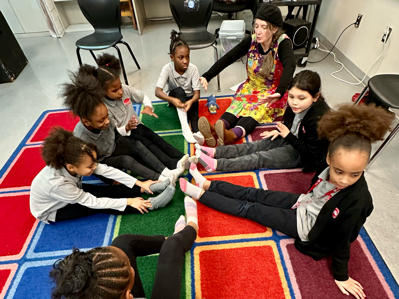 A group of children are sitting in a circle on a rug.