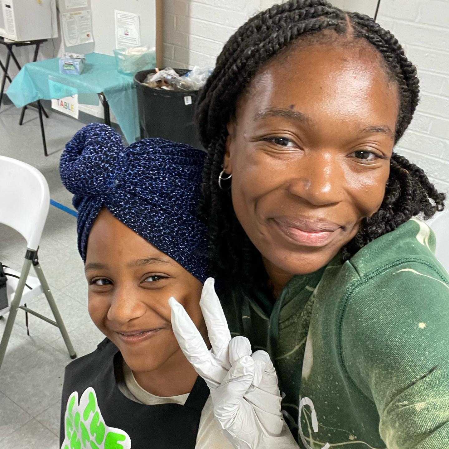 A woman and a child are posing for a picture and the woman is wearing gloves.