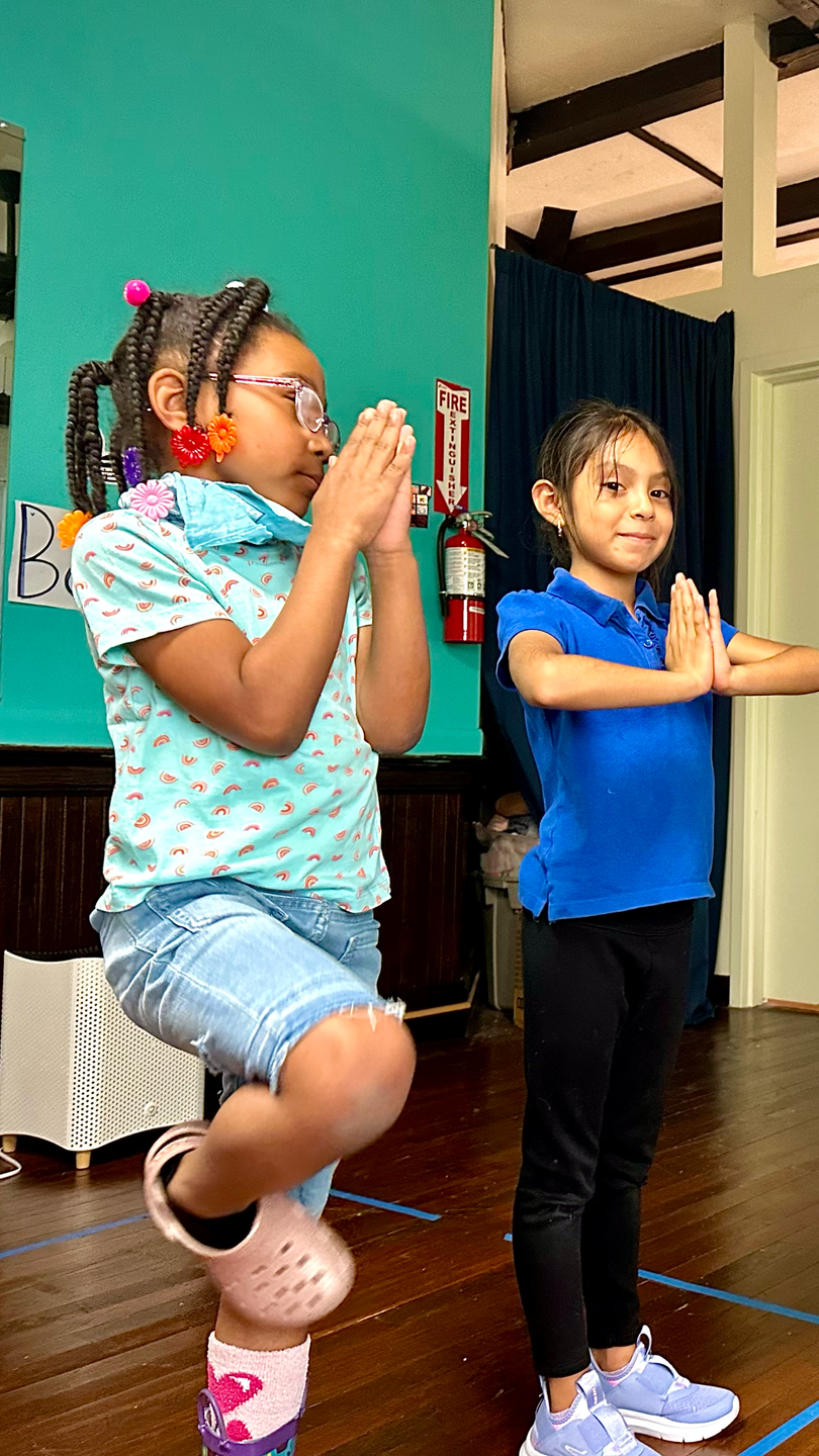 Two young girls are standing next to each other in a room.