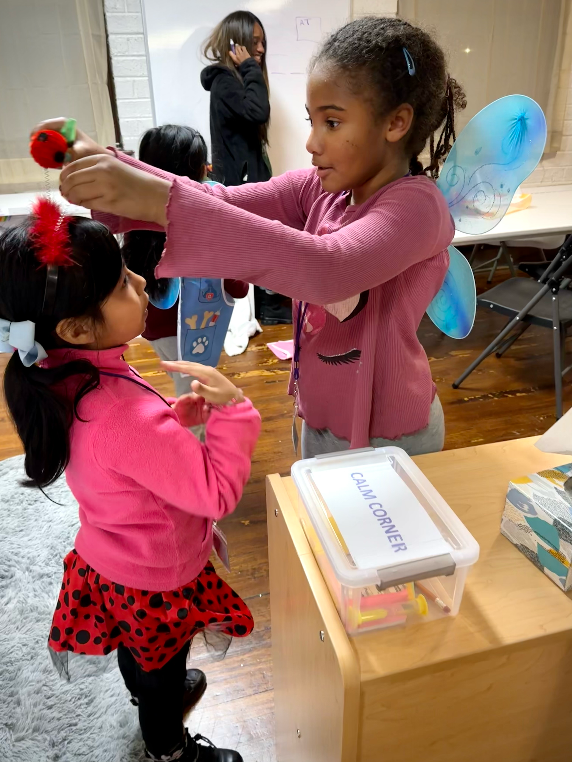 Two little girls are standing next to each other in a room.