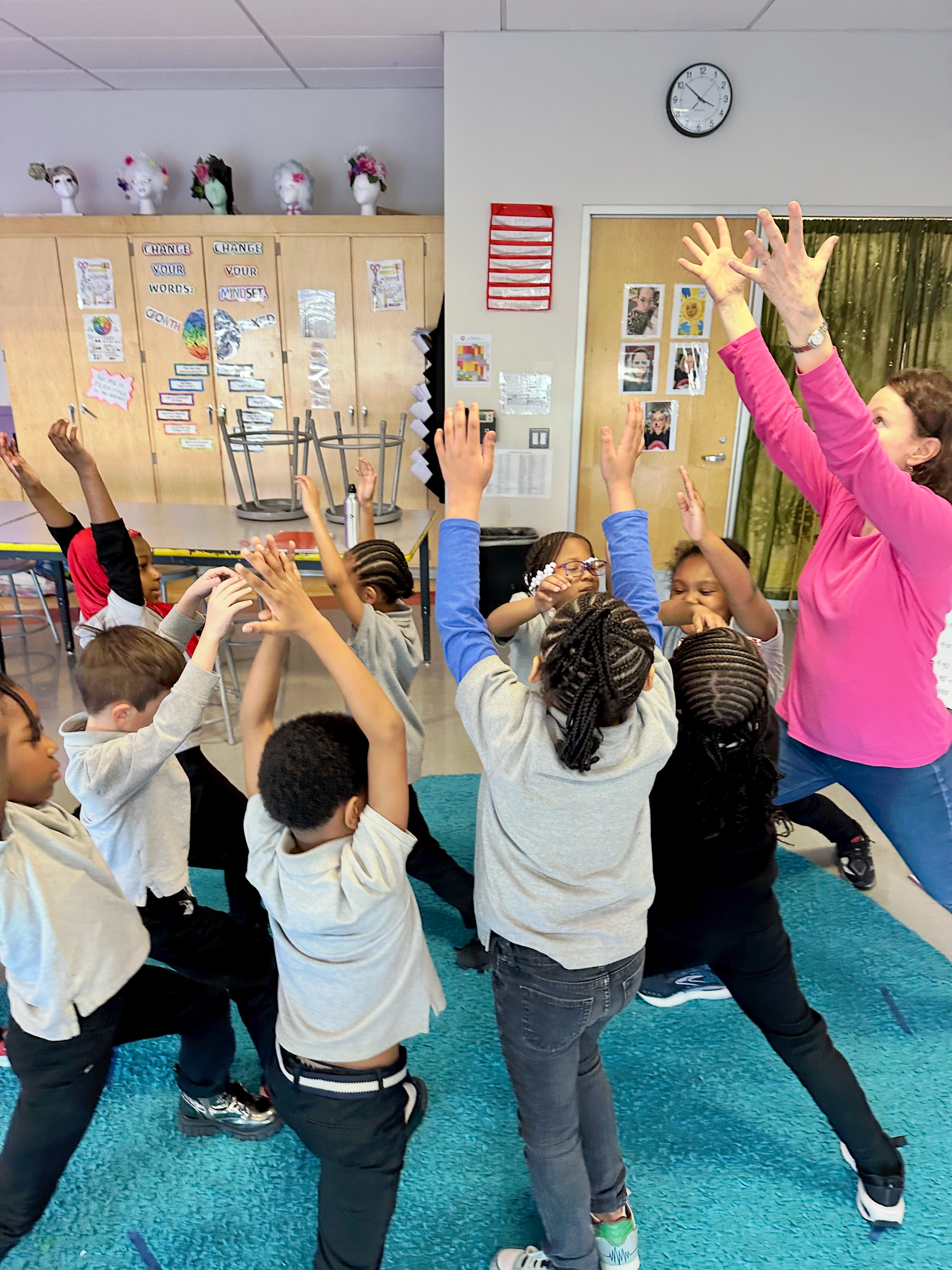 A group of children are standing in a circle with their hands in the air