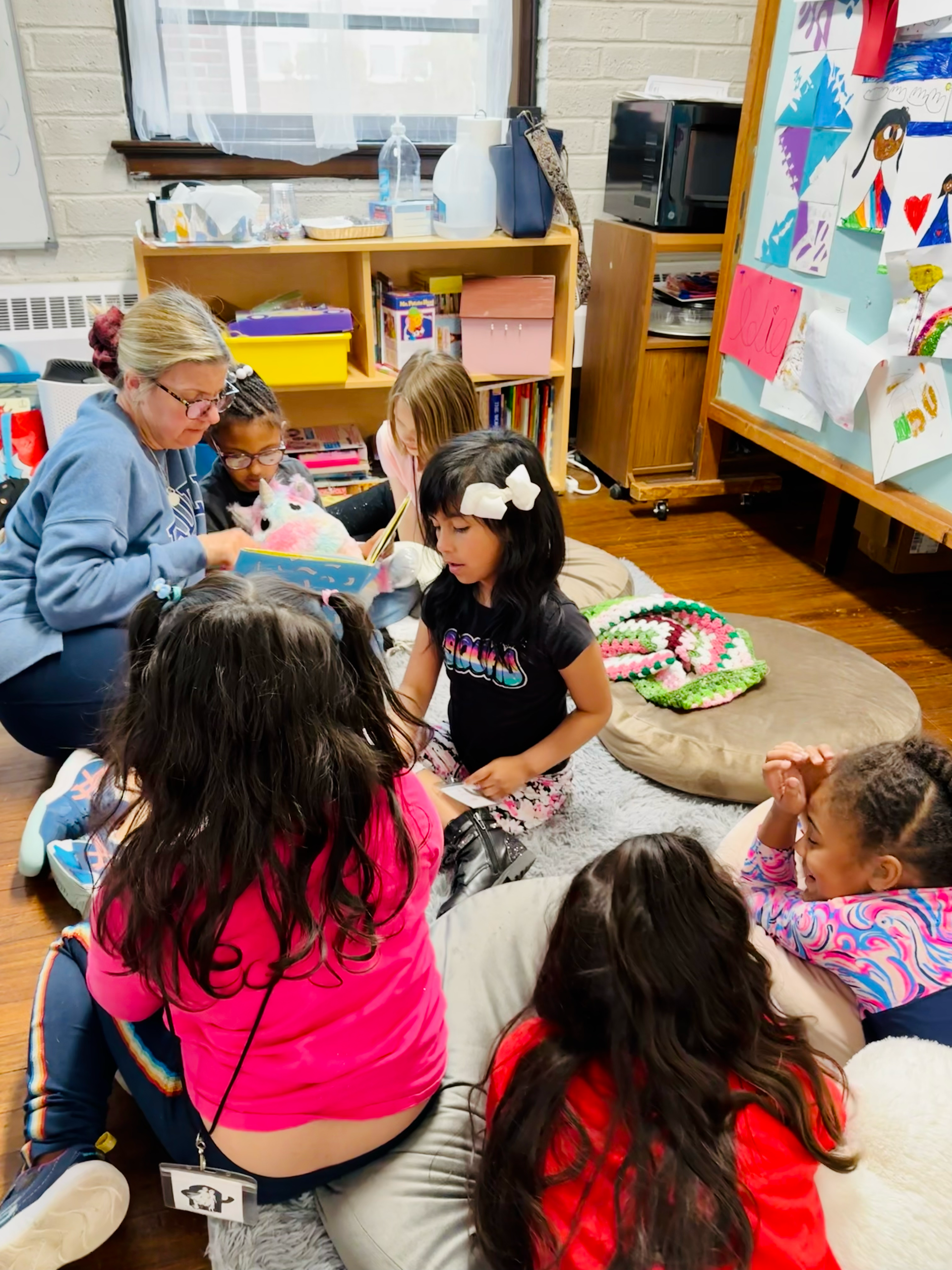 A group of children are sitting on the floor in a classroom.