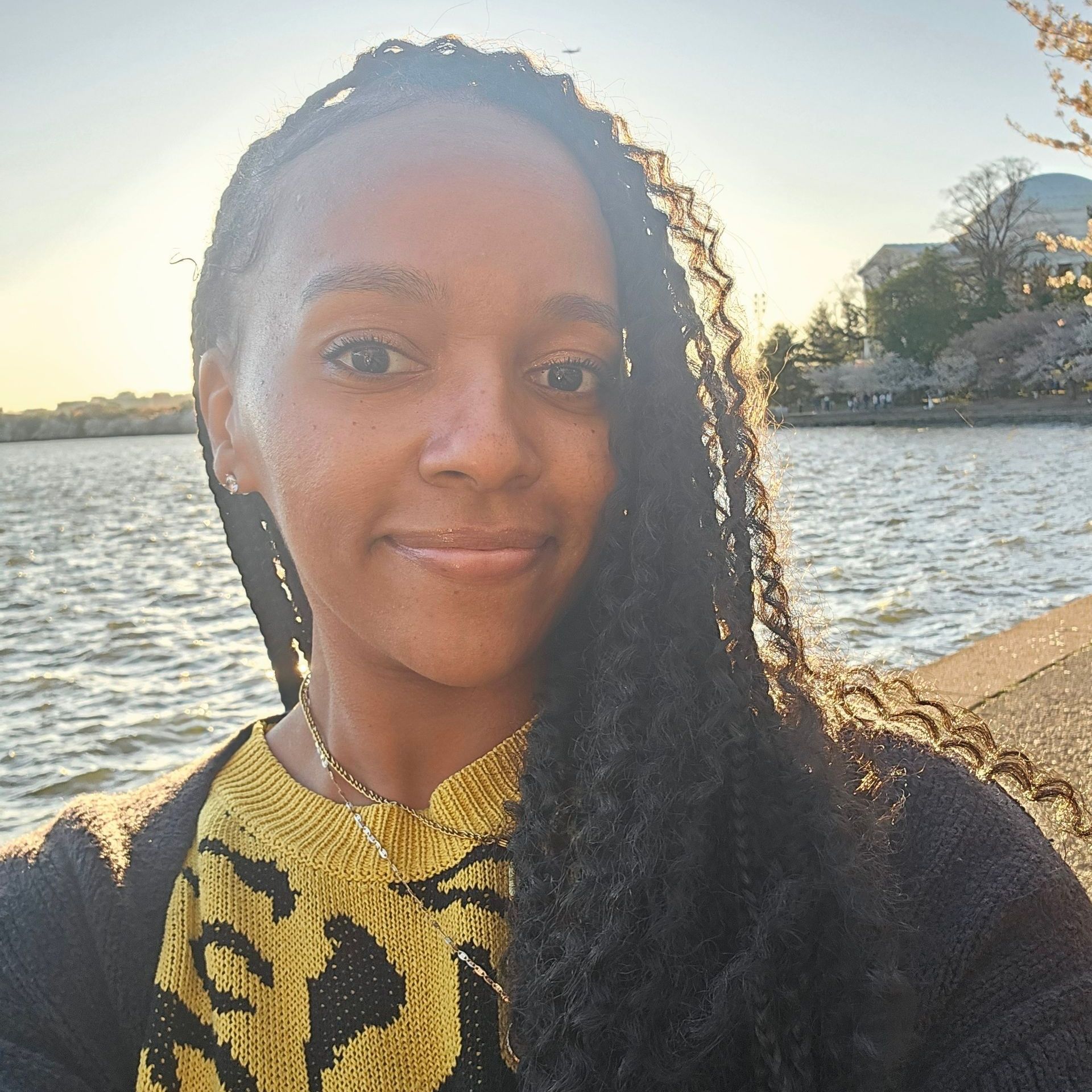 A woman is taking a selfie in front of a body of water.