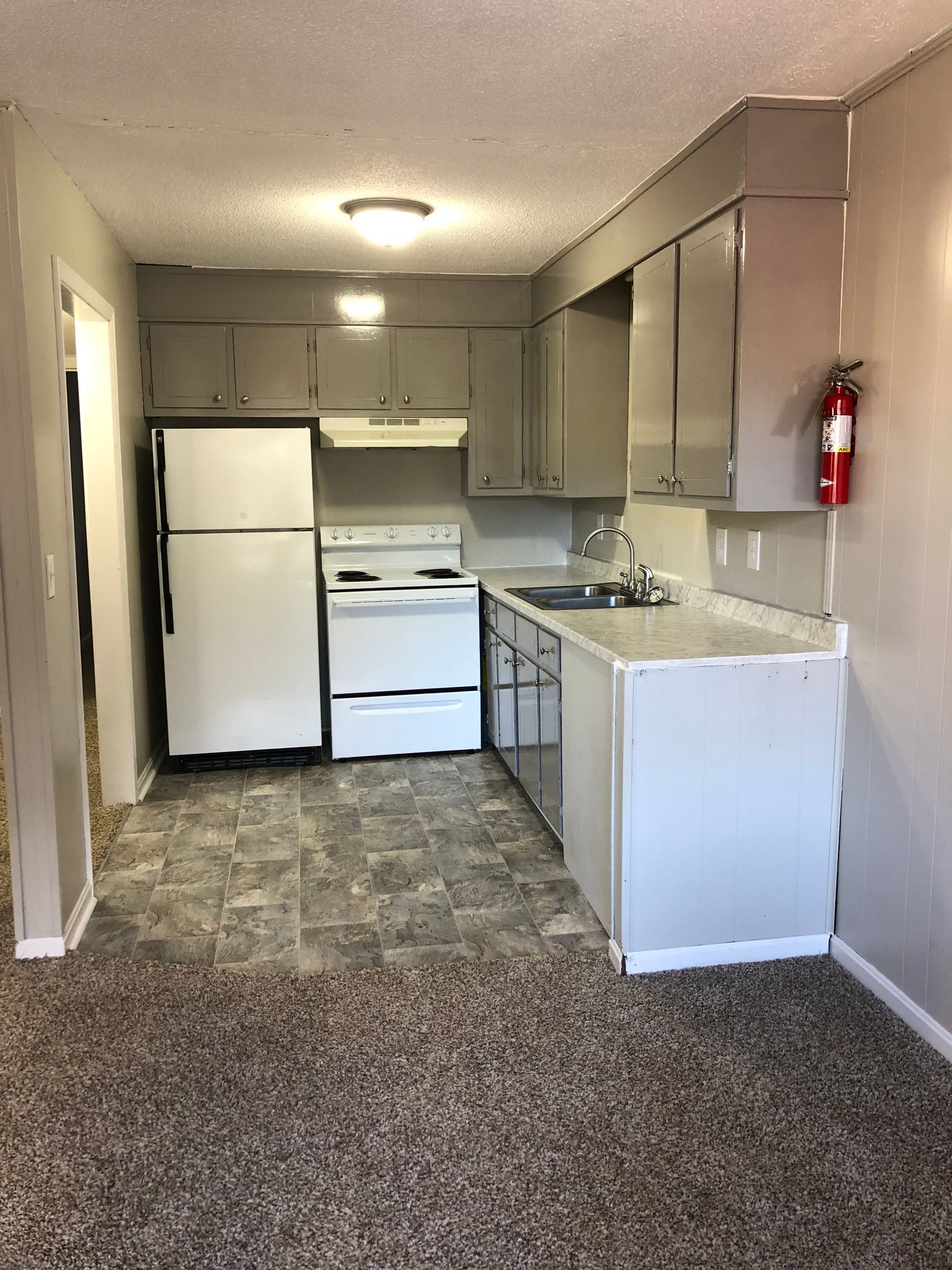 a kitchen with a refrigerator , stove , sink and fire extinguisher .