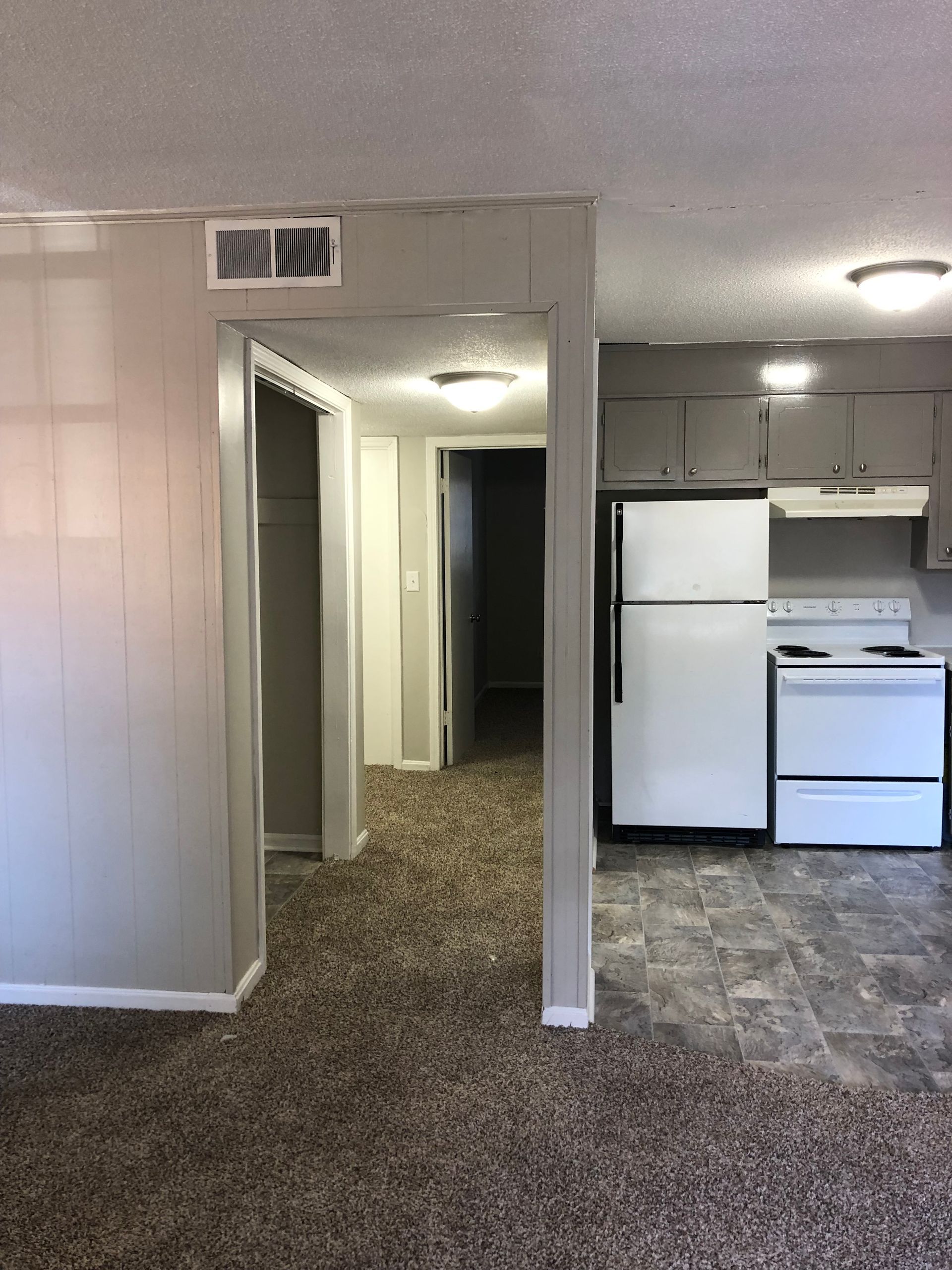 an empty kitchen with a refrigerator , stove , and sink .