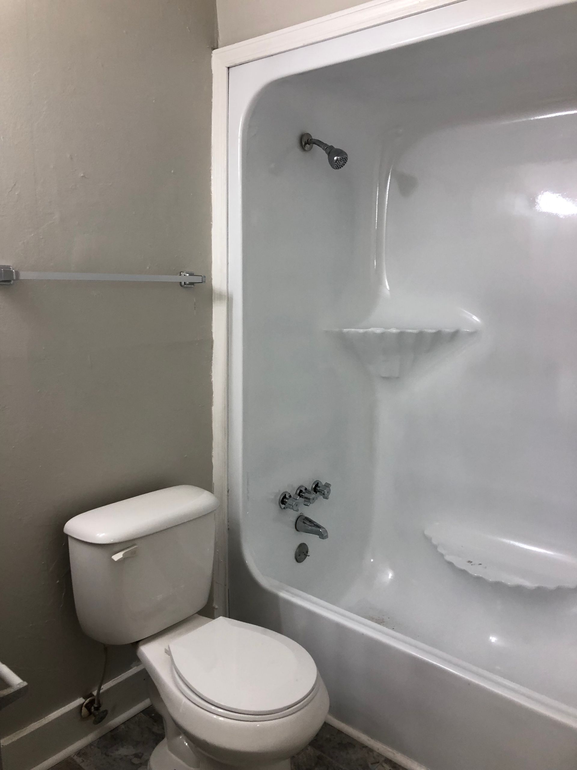 a bathroom with a toilet , tub and shower .