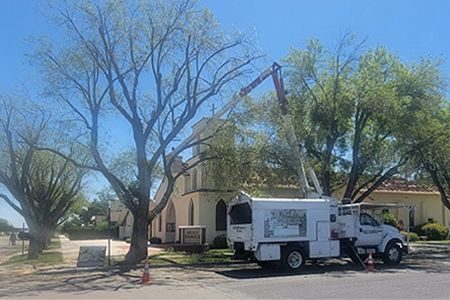 A white truck with a crane attached to it is parked in front of a church.