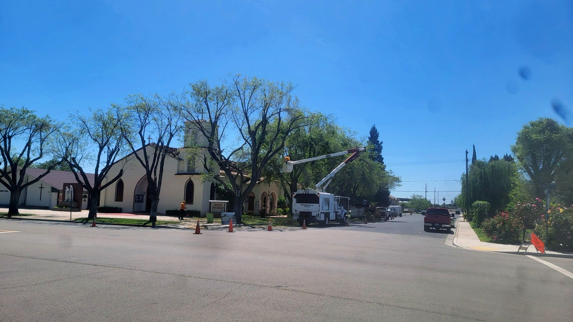 A white truck is driving down a street in front of a church.