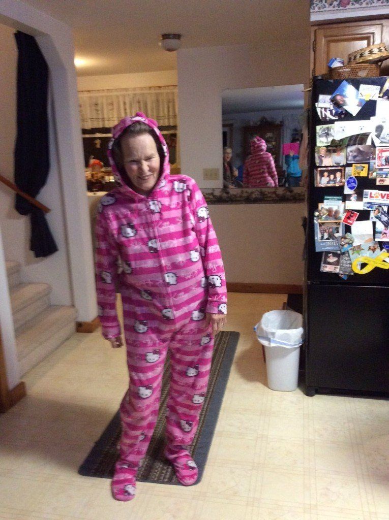 Person in pink Hello Kitty onesie, standing on a rug inside a home. A reflection is seen in the mirror.