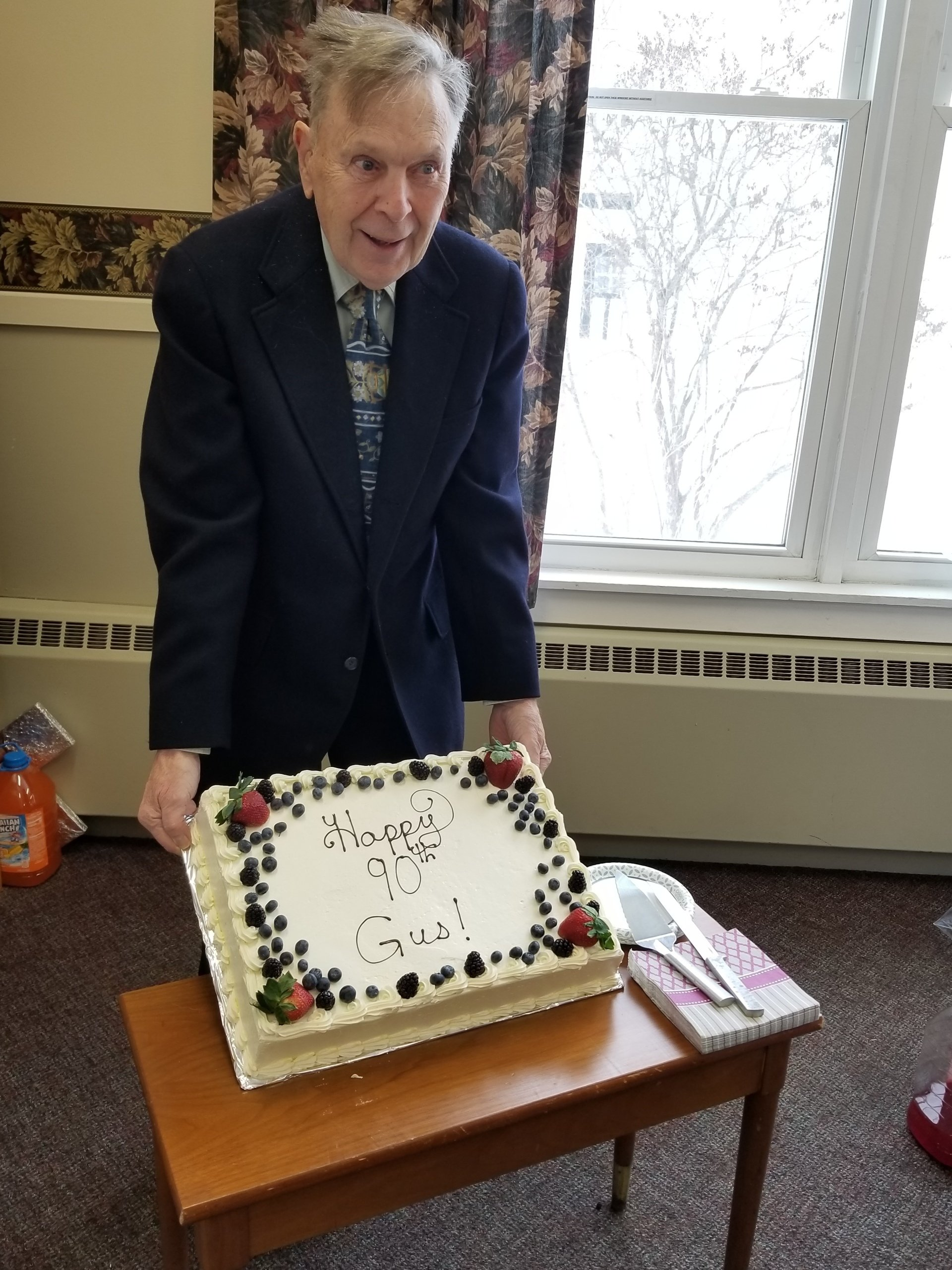 Man in suit holding a cake with 