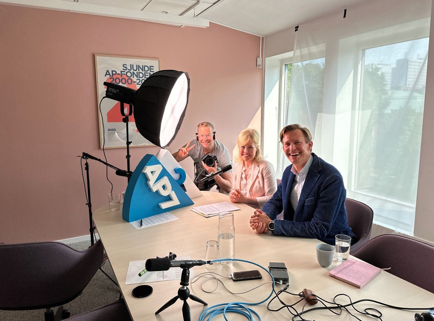 Woman tending to a flock of sheep in a sunny field near a forest.