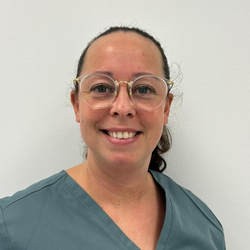 Eine Frau mit Brille lächelt in einem türkisfarbenen Oberteil in die Kamera.