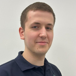 Mann in dunkelblauem Polohemd, lächelnd, schaut in die Kamera.