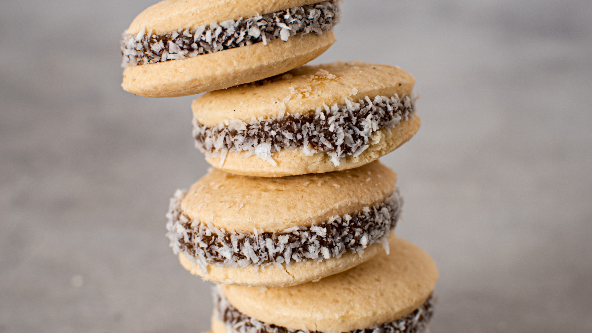 Stack of alfajores cookies with coconut flakes around dulce de leche filling.