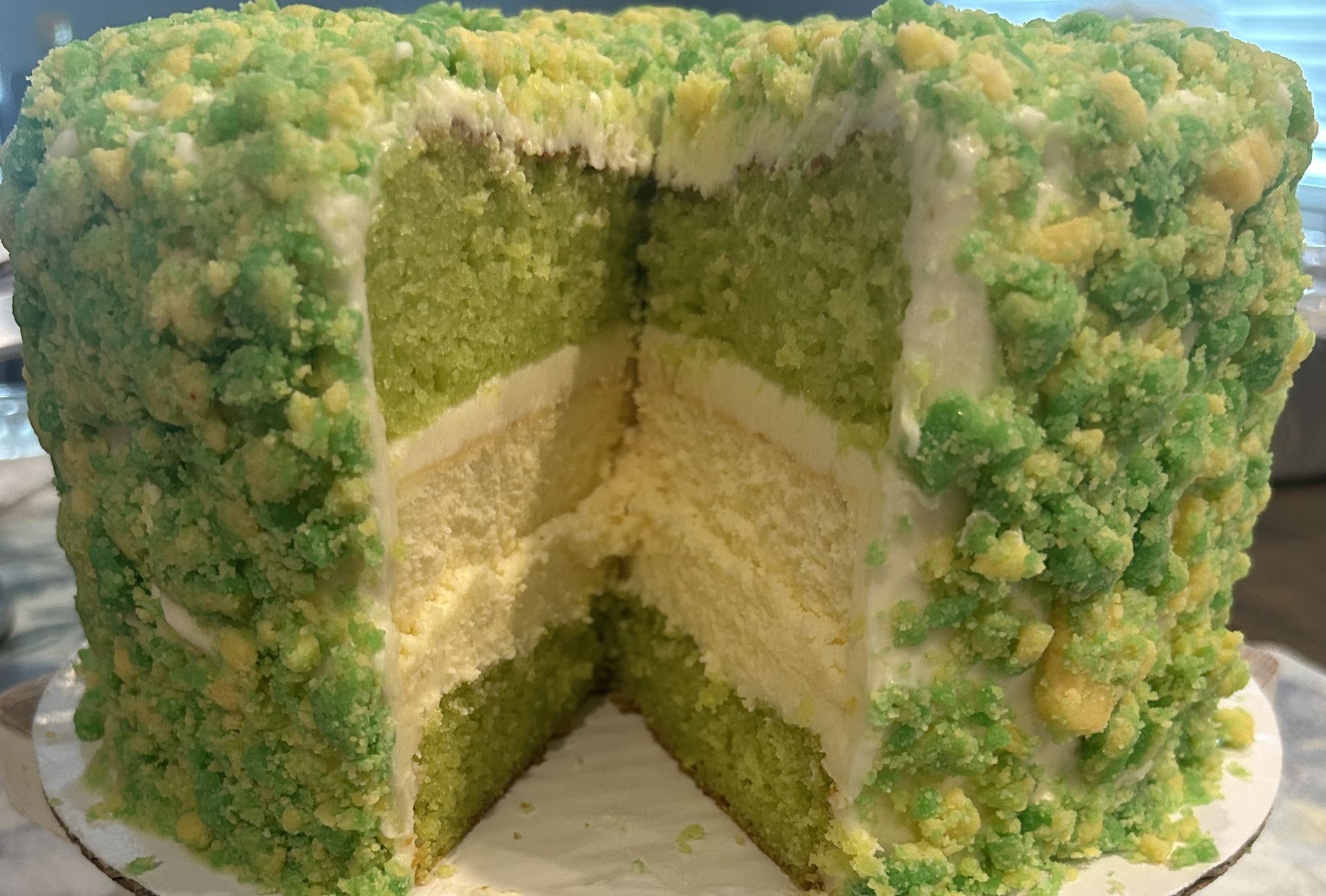 Green cake with a crumbly topping, cut to reveal layers and frosting.