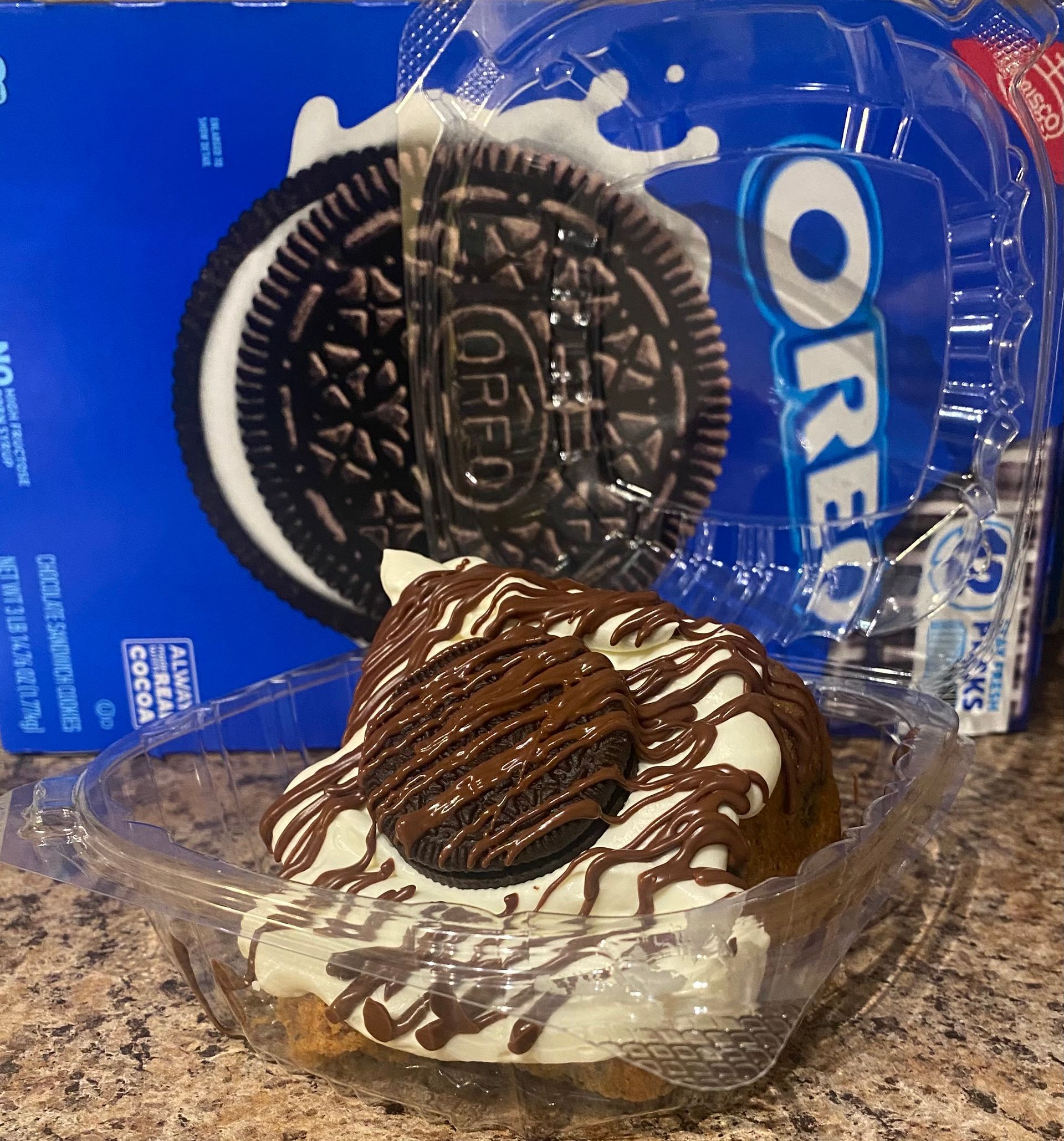 Oreo cookie dessert with whipped cream and chocolate drizzle, near a box and package of Oreos.