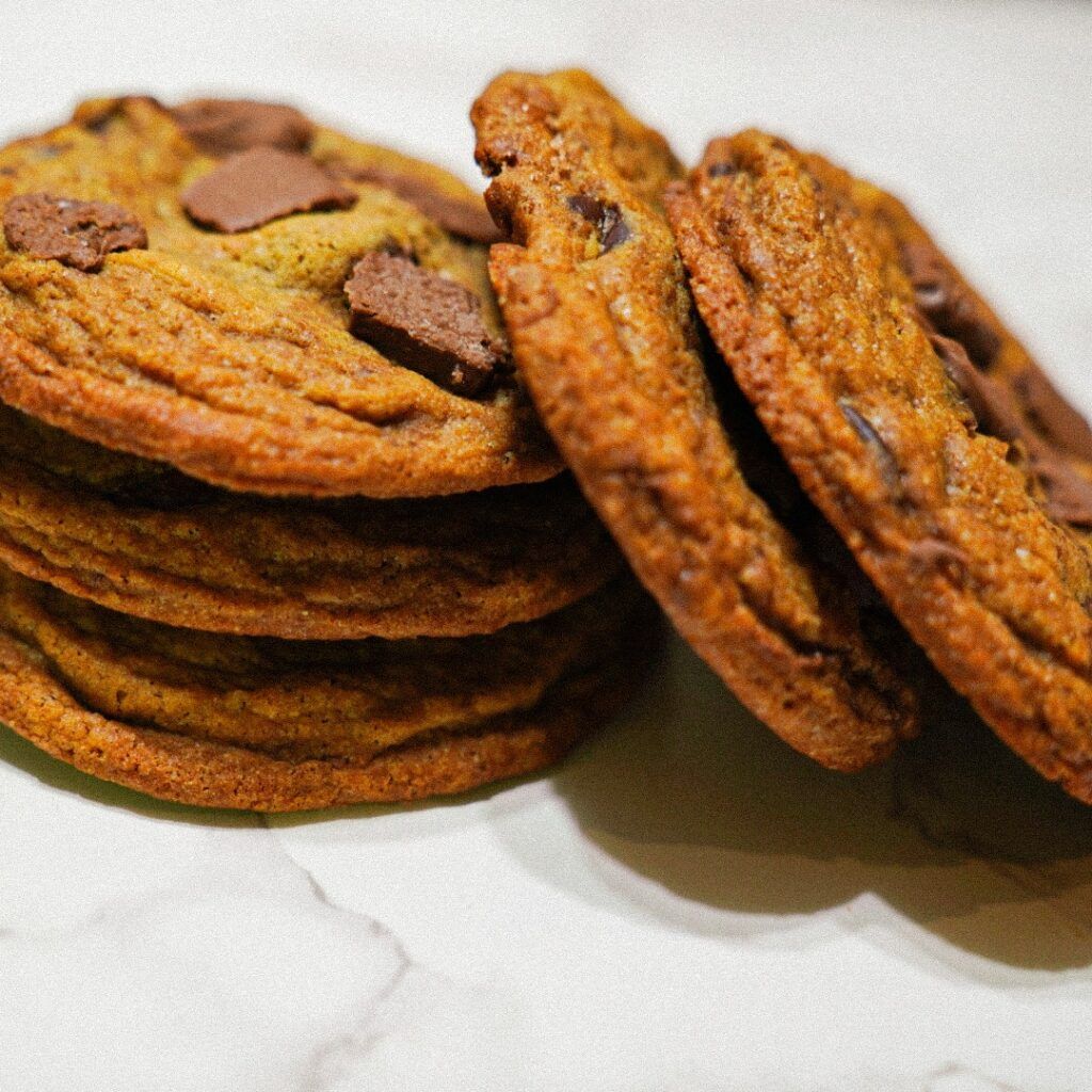 Stack of chocolate chip cookies, close-up, with visible chocolate chunks and golden-brown color.