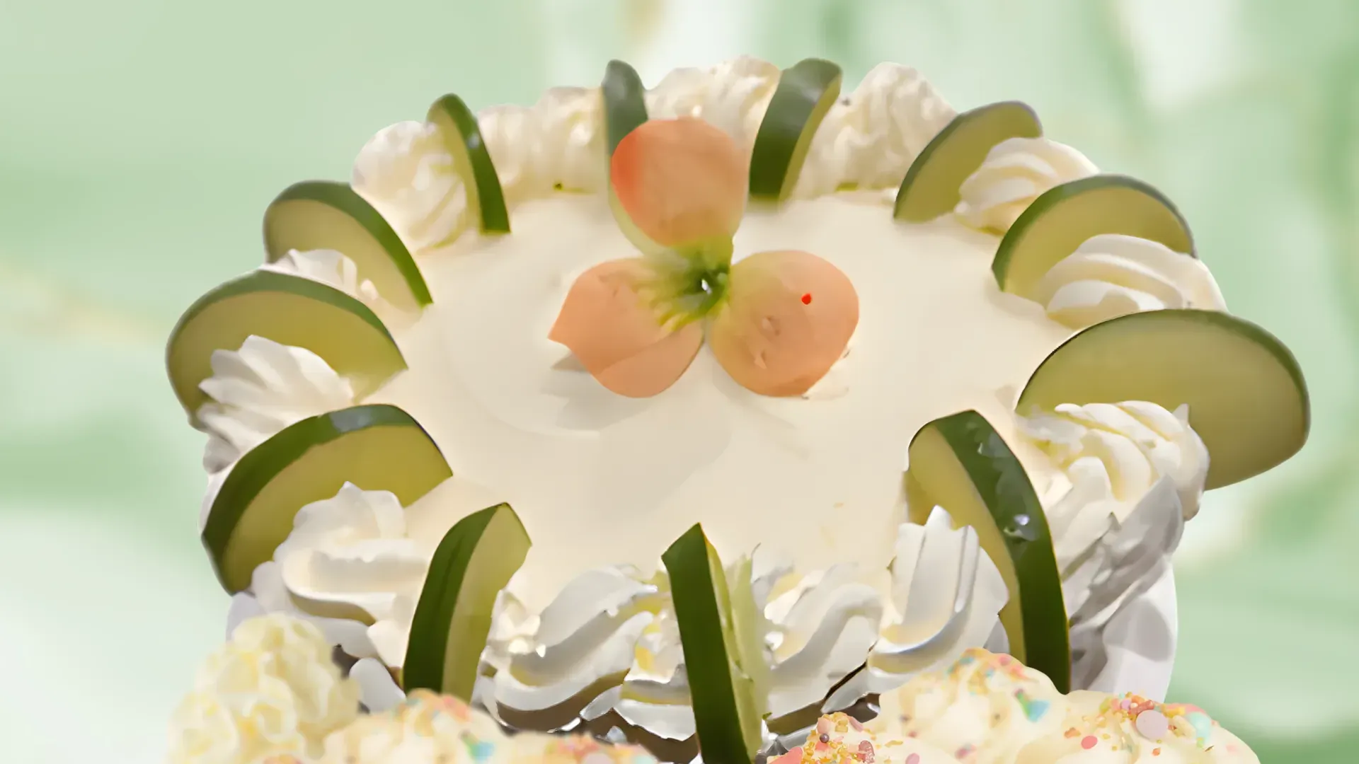 Cake with white frosting, lime slices, and a flower on top.