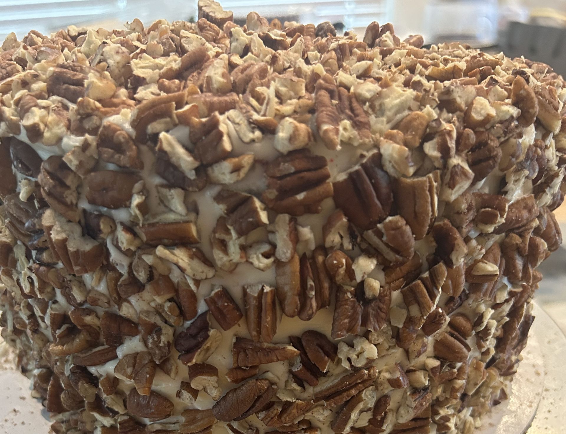 Cake covered in cream frosting and chopped pecans.