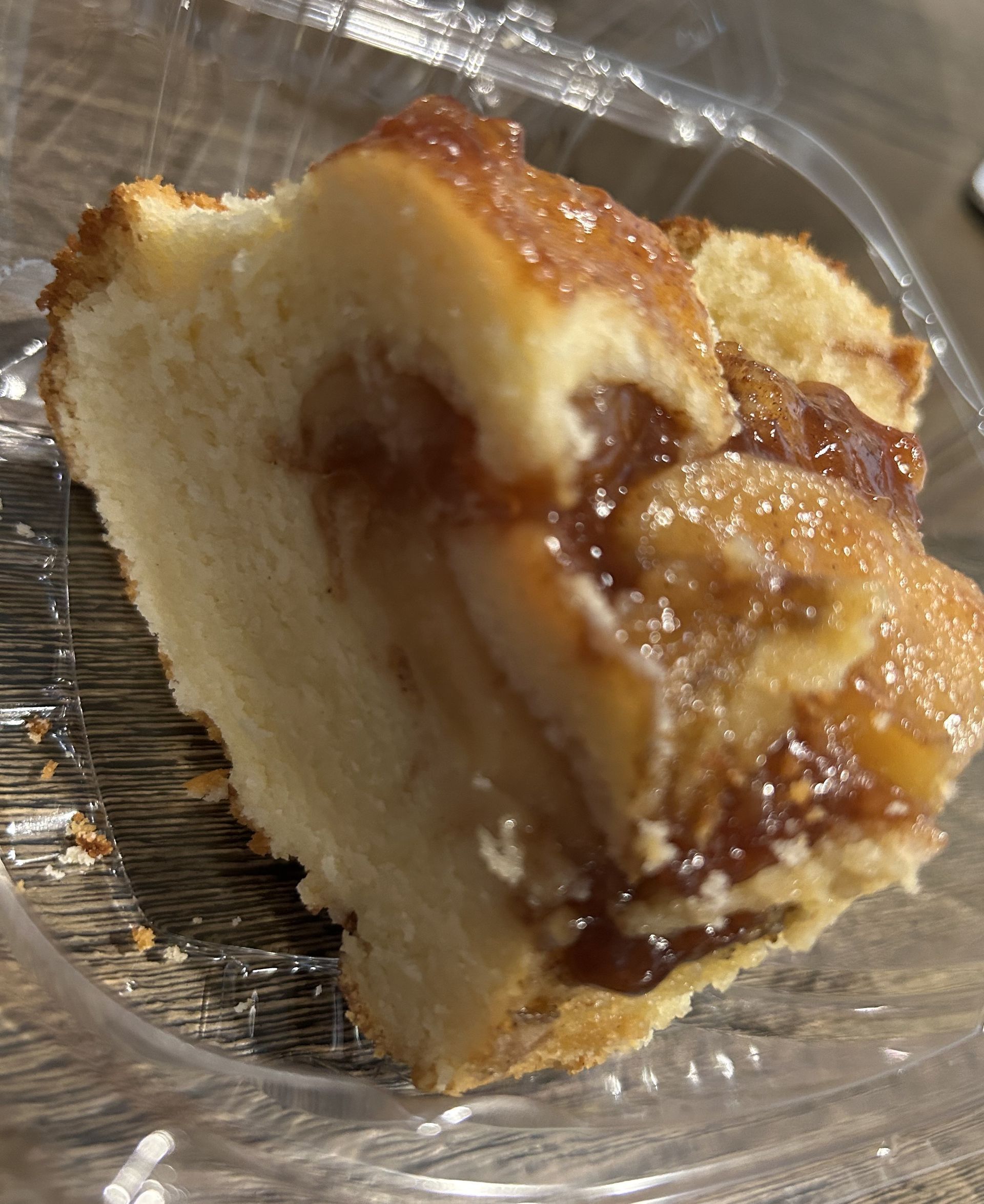 Slice of coffee cake with caramel topping in a clear plastic container.