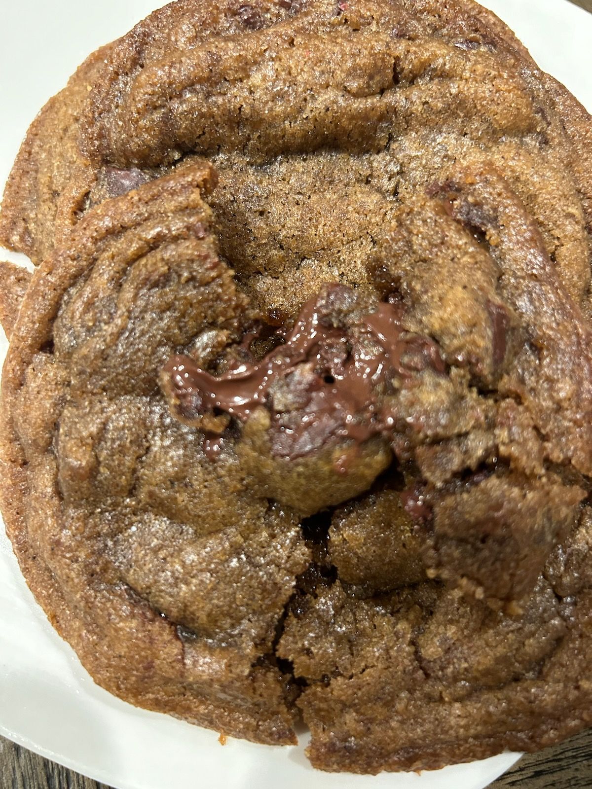 Close-up of a large, soft chocolate cookie with melted chocolate visible.
