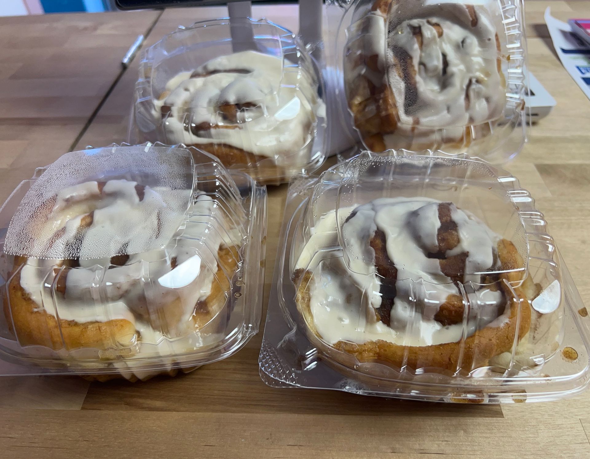 Four cinnamon rolls with icing, packaged in clear plastic containers.