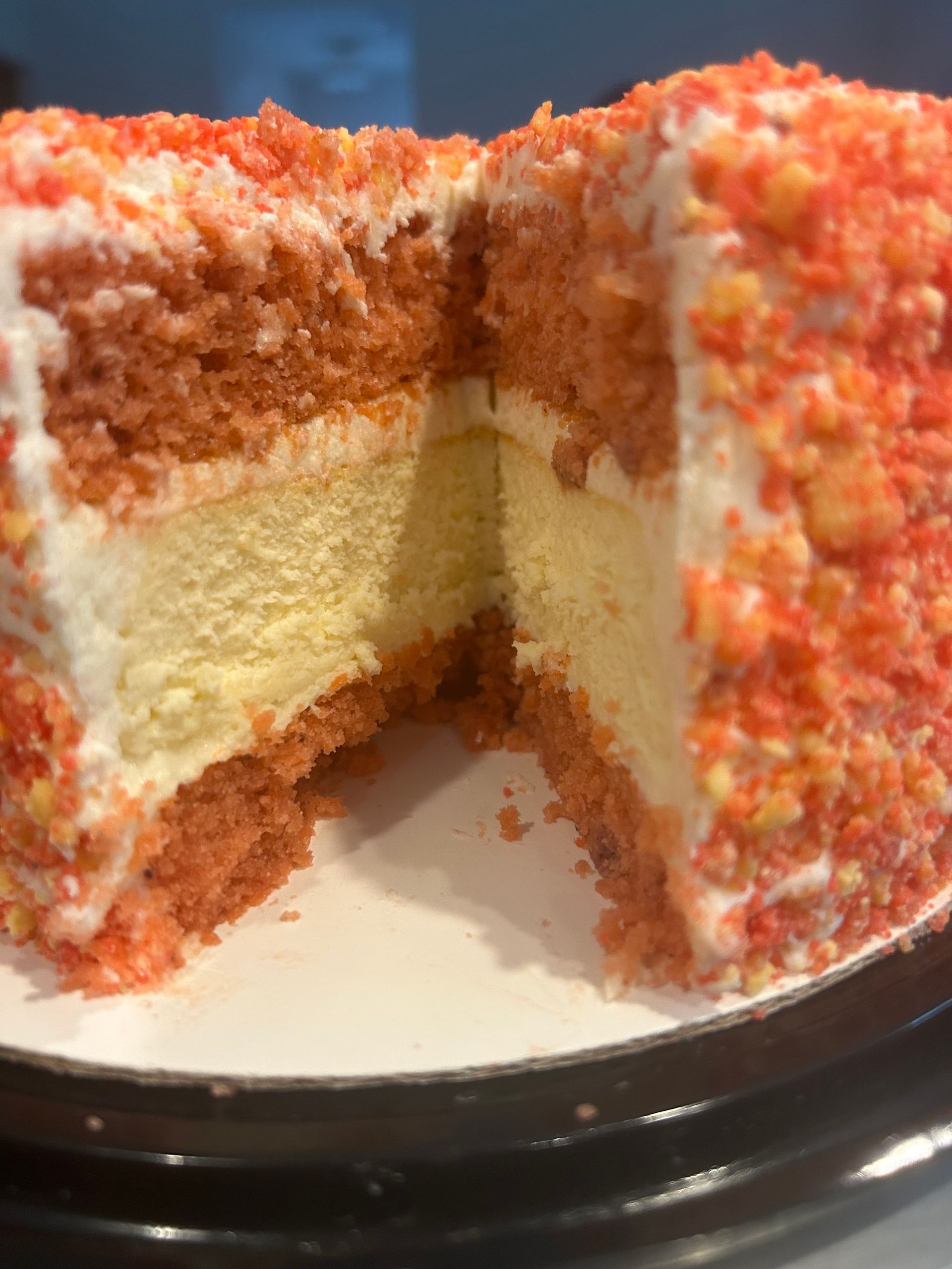 Cake with red crumb coating, cut open to reveal white frosting and yellow filling.