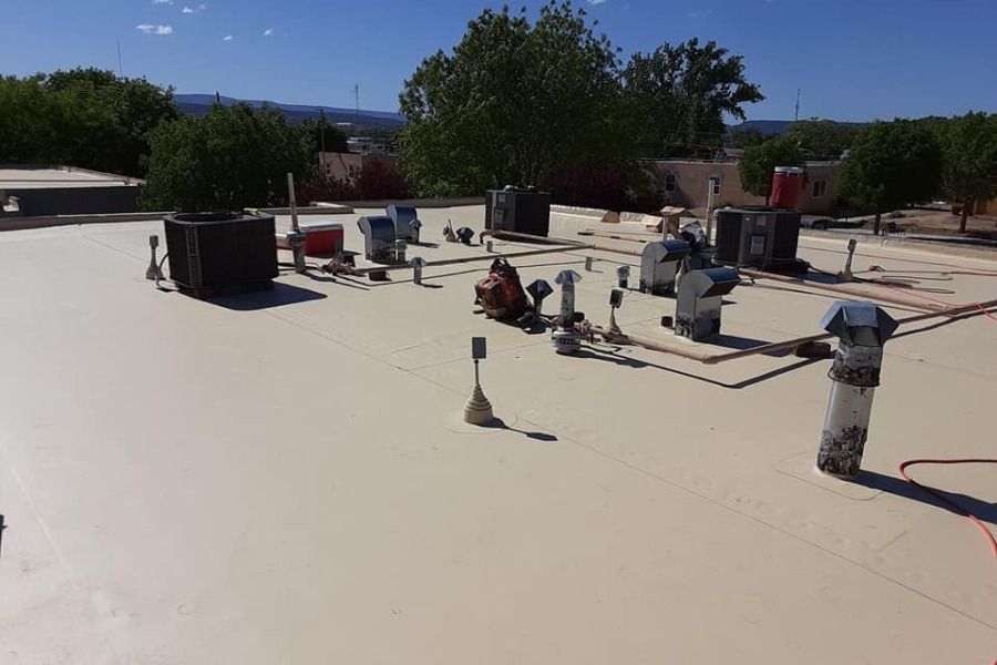 Workers installing equipment on a flat white rooftop under a clear blue sky.