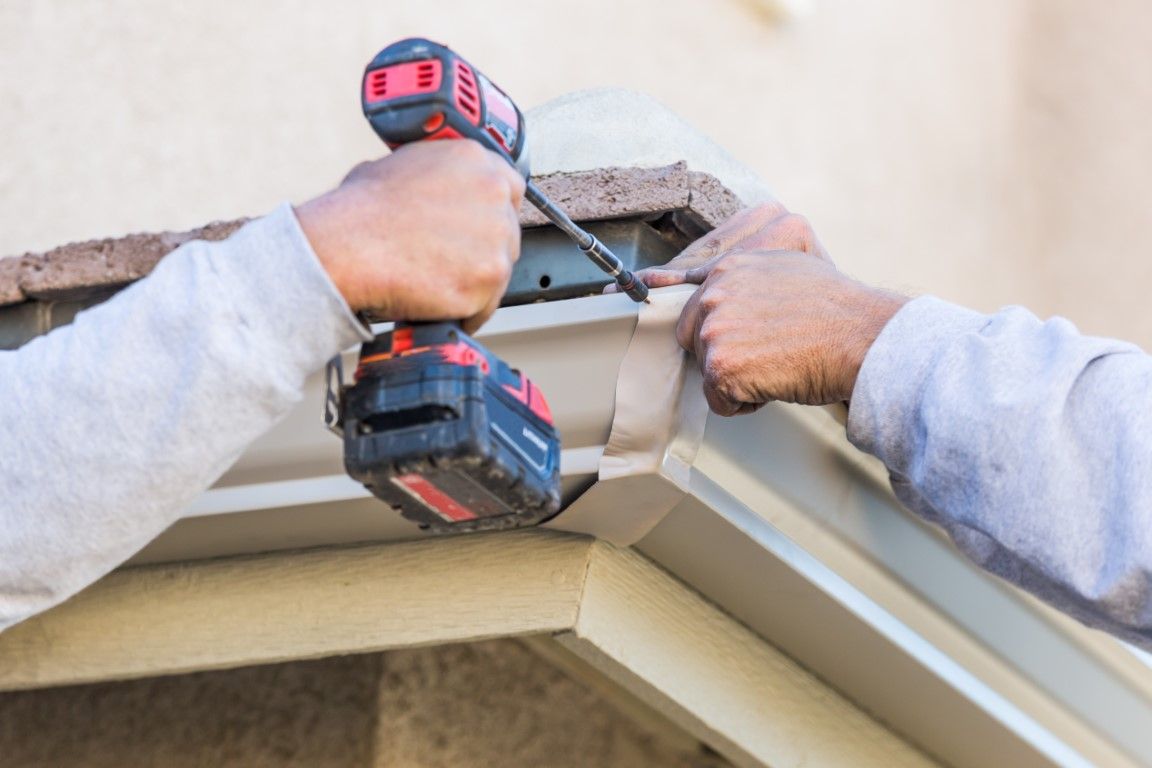 Professional using drill to install gutters up close picture of hands