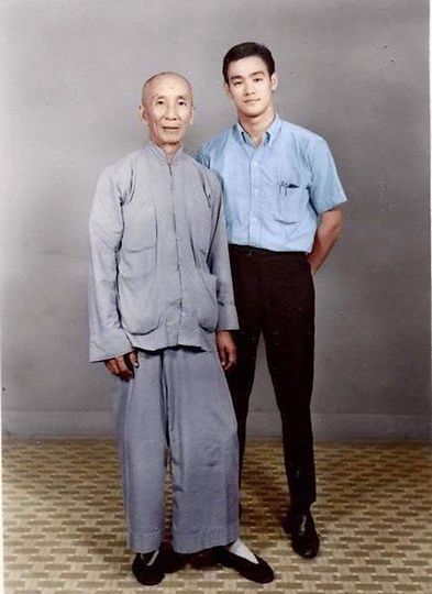 Two men standing next to each other with one wearing a blue shirt