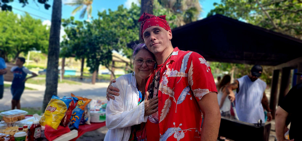 A man and a woman are posing for a picture at a picnic table.