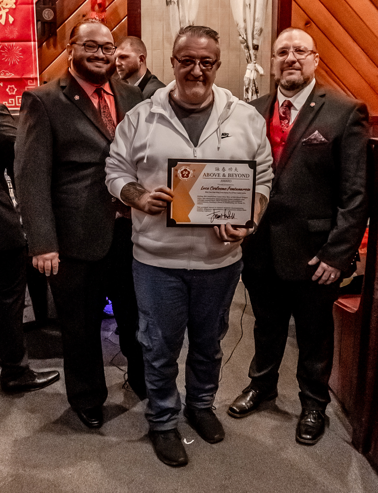 Three men are posing for a picture and one of them is holding a certificate