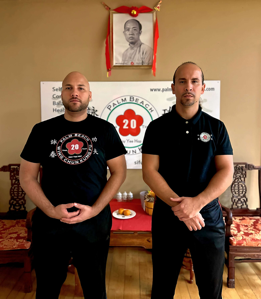 Two men standing in front of a palm beach sign