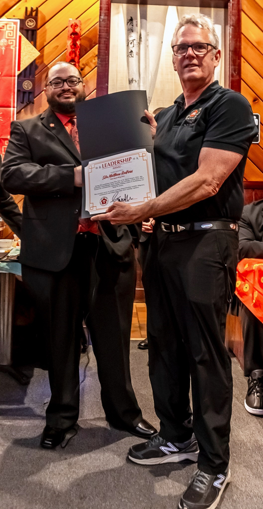 Two men are standing next to each other holding a certificate.