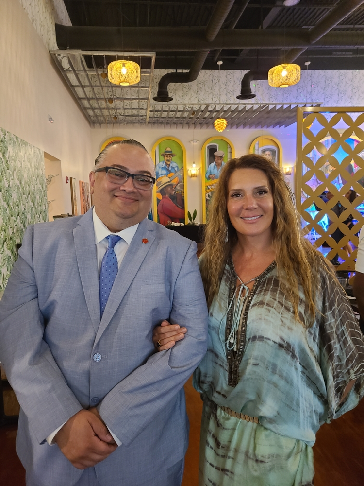 A man in a suit and tie is standing next to a woman in a blue dress.