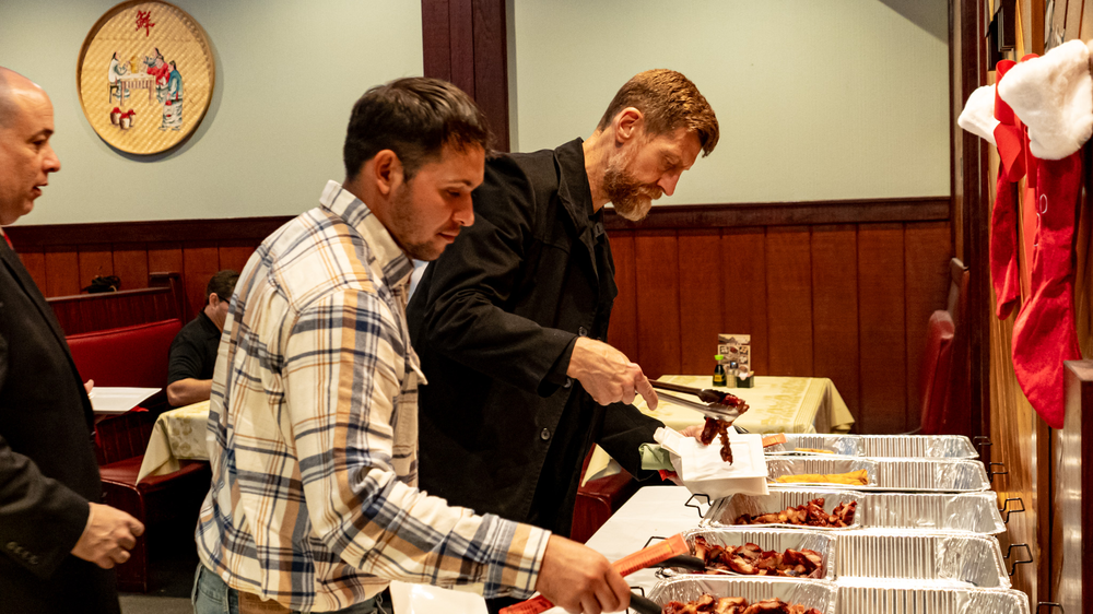 A group of men are standing at a buffet line in a restaurant.