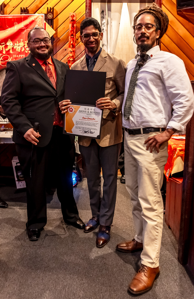 Three men are standing next to each other in a room holding a certificate.