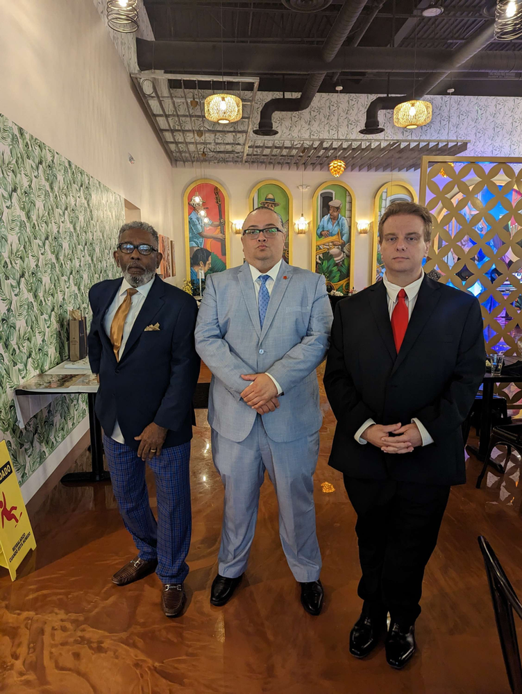 Three men in suits and ties are standing next to each other in a room.