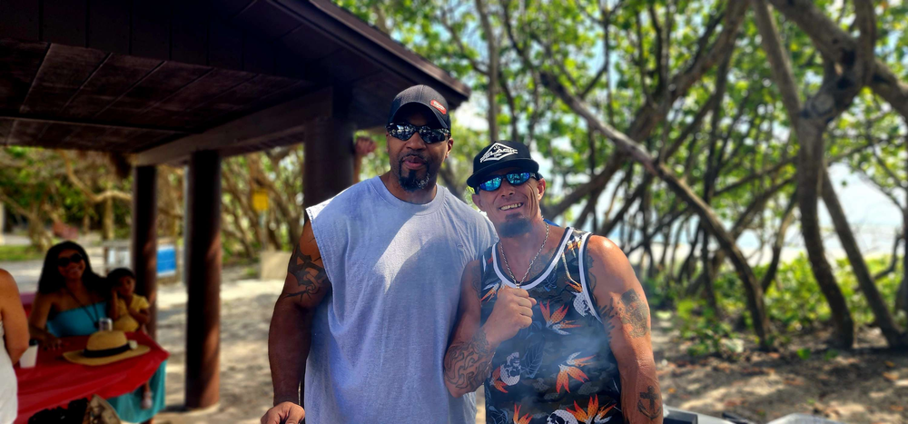 Two men are standing next to each other on a beach.