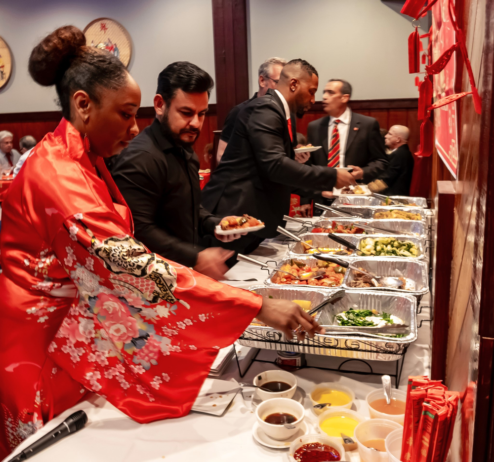 A woman in a red robe is serving food at a buffet