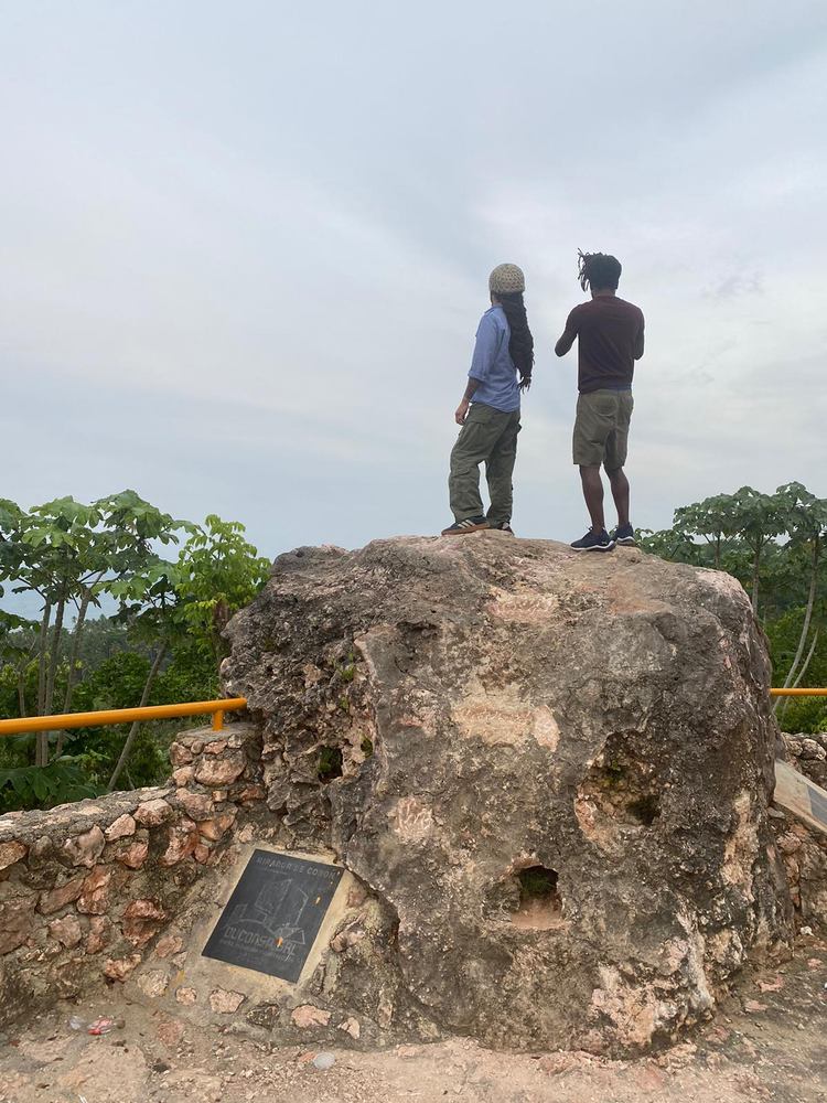 Two people are standing on top of a large rock.