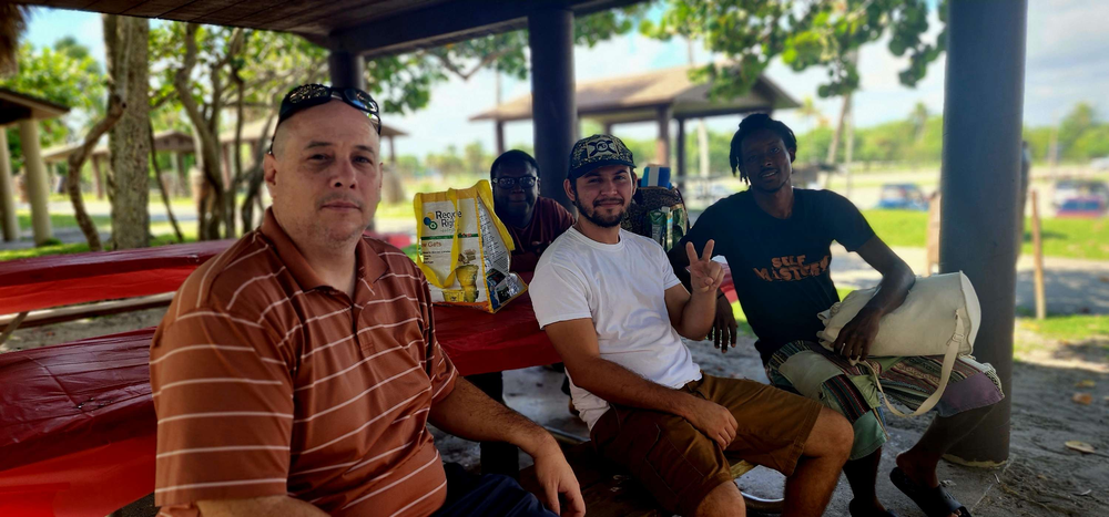 A group of people are sitting at a picnic table in a park.