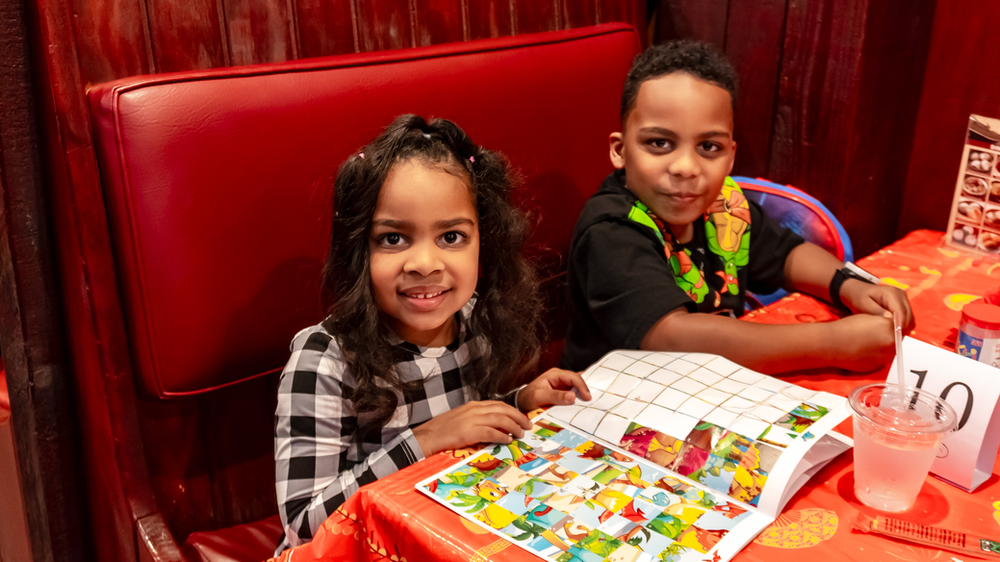 A boy and a girl are sitting at a table in a restaurant.