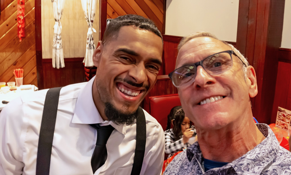 Two men are posing for a picture together in a restaurant.