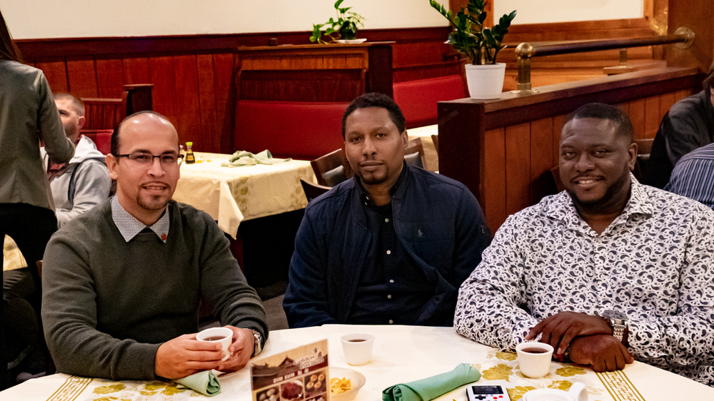 Three men are sitting at a table in a restaurant.