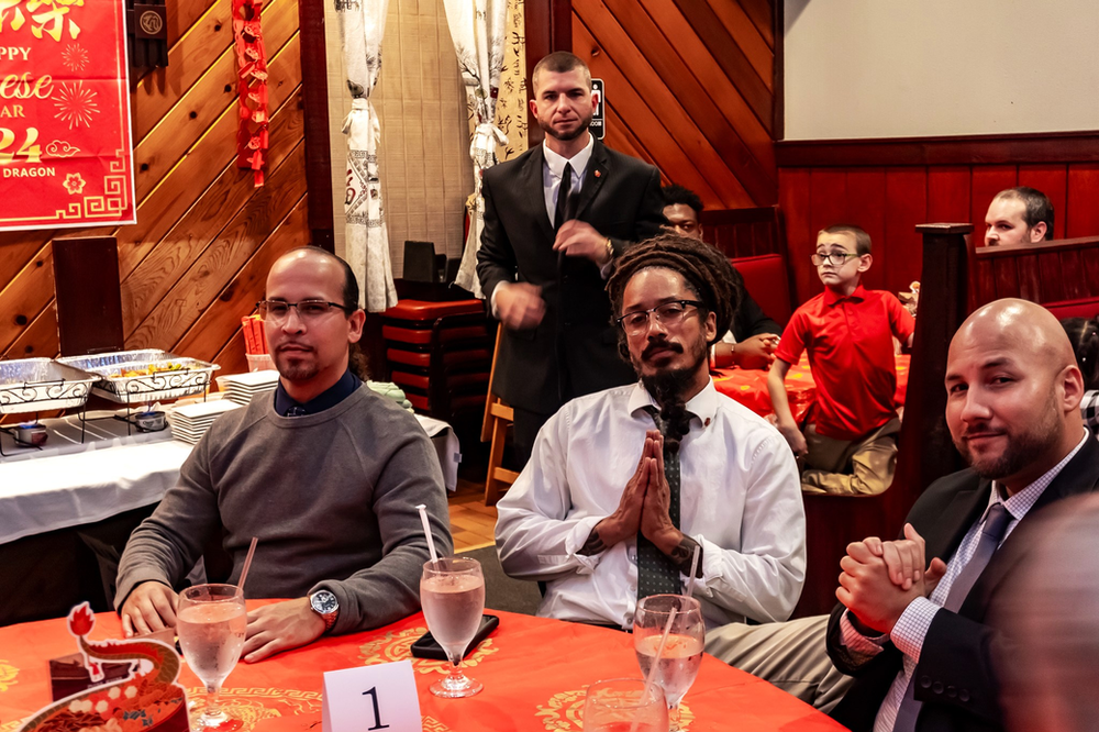 A group of men are sitting at a table with a number 1 on it