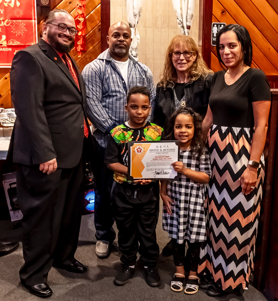 A group of people posing for a picture with a child holding a certificate