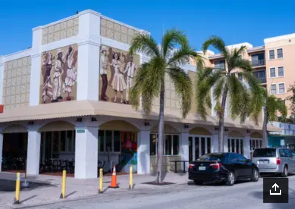 A white building with palm trees in front of it