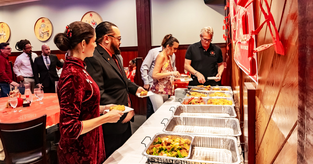 A group of people are standing around a buffet line at a restaurant.