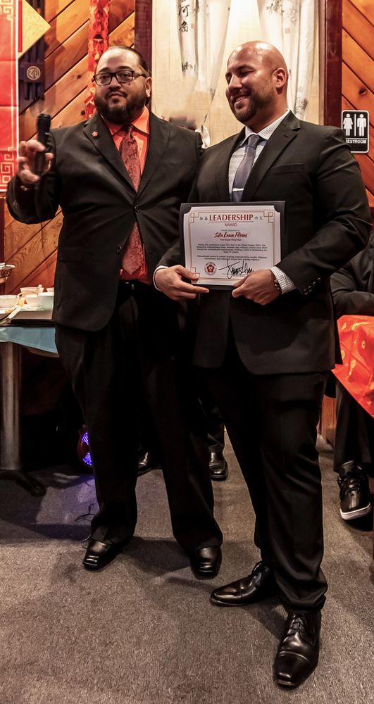 Two men in suits and ties are standing next to each other holding a certificate.